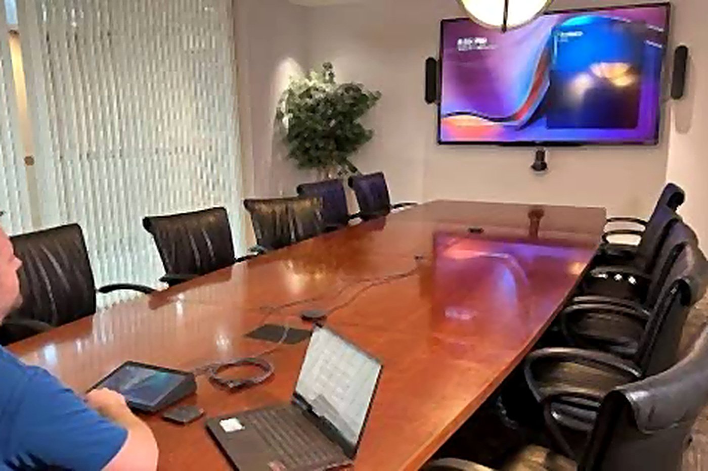 An executive conference room with a large table, display and conferencing audio loading=